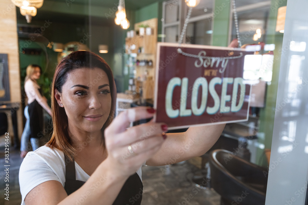 Female hairdresser holding Closed sign board at hair salon Stock Photo