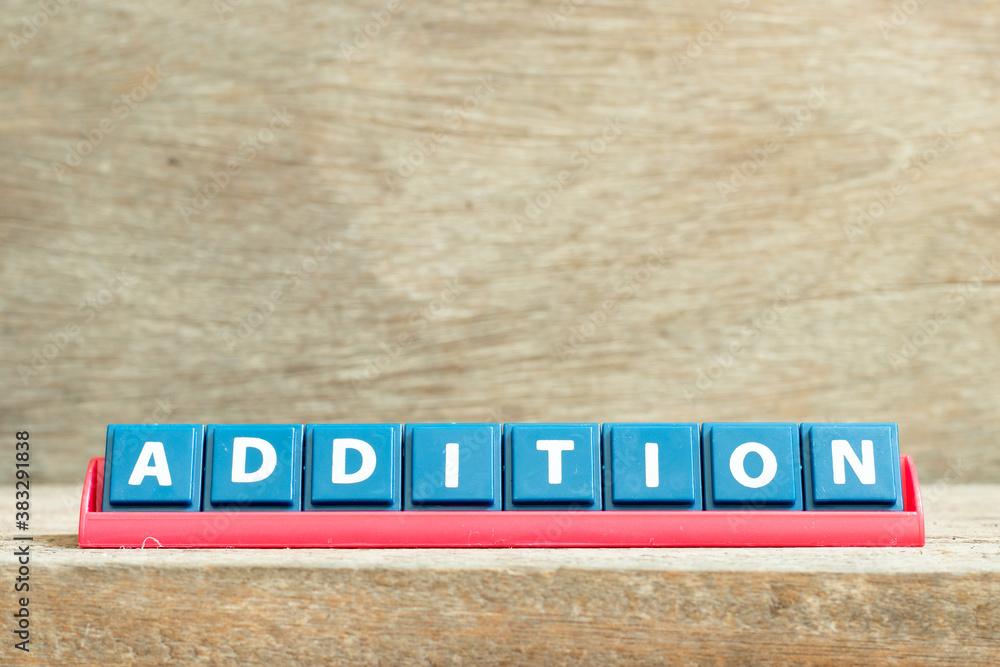 Tile letter on red rack in word addition on wood background Tile letter on red rack in word addition on wood background