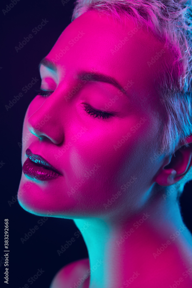 Close up. Portrait of female fashion model in neon light on dark studio background. Beautiful caucasian woman with trendy make-up and well-kept skin. Vivid style, beauty concept. Close up. Copyspace Close up. Portrait of female fashion model in neon light on dark studio background. Beautiful caucasian woman with trendy make-up and well-kept skin. Vivid style, beauty concept. Close up. Copyspace