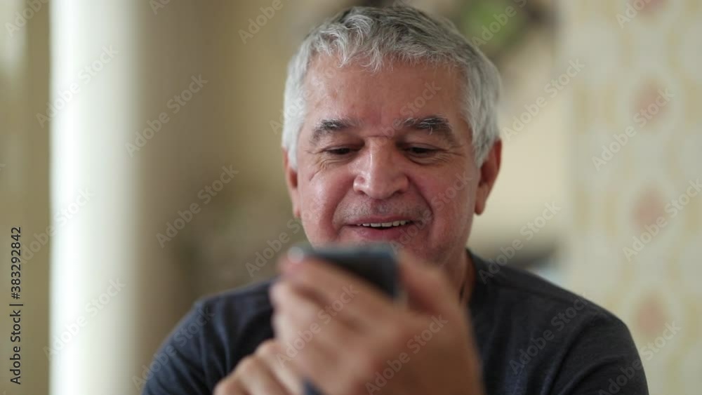 Older man looking at cellphone screen reacting positively to good news Older man looking at cellphone screen reacting positively to good news