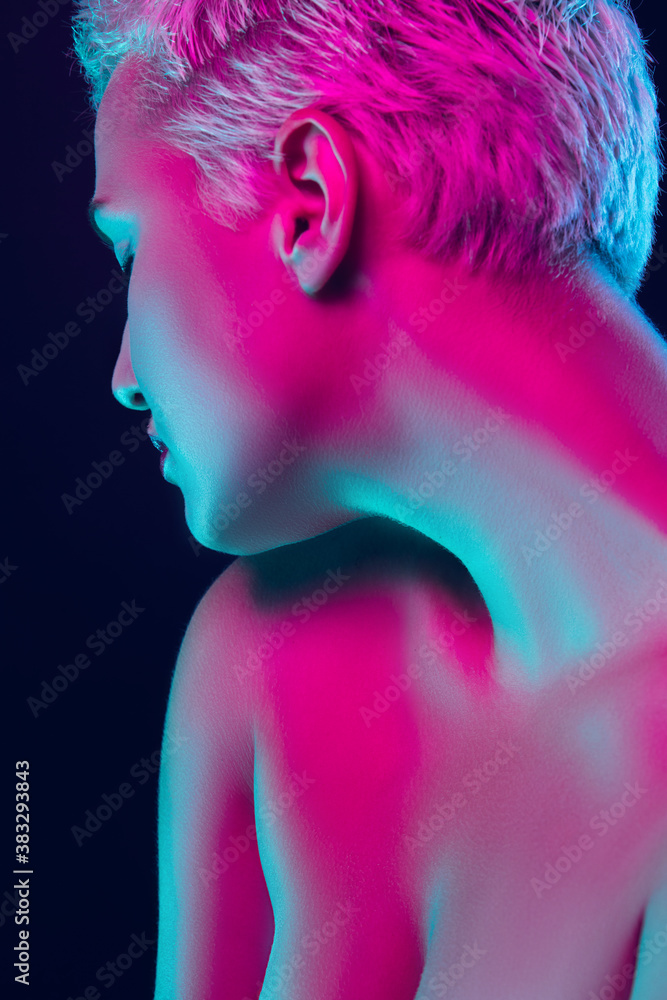 Tensioned. Portrait of female fashion model in neon light on dark studio background. Beautiful caucasian woman with trendy make-up and well-kept skin. Vivid style, beauty concept. Close up. Copyspace