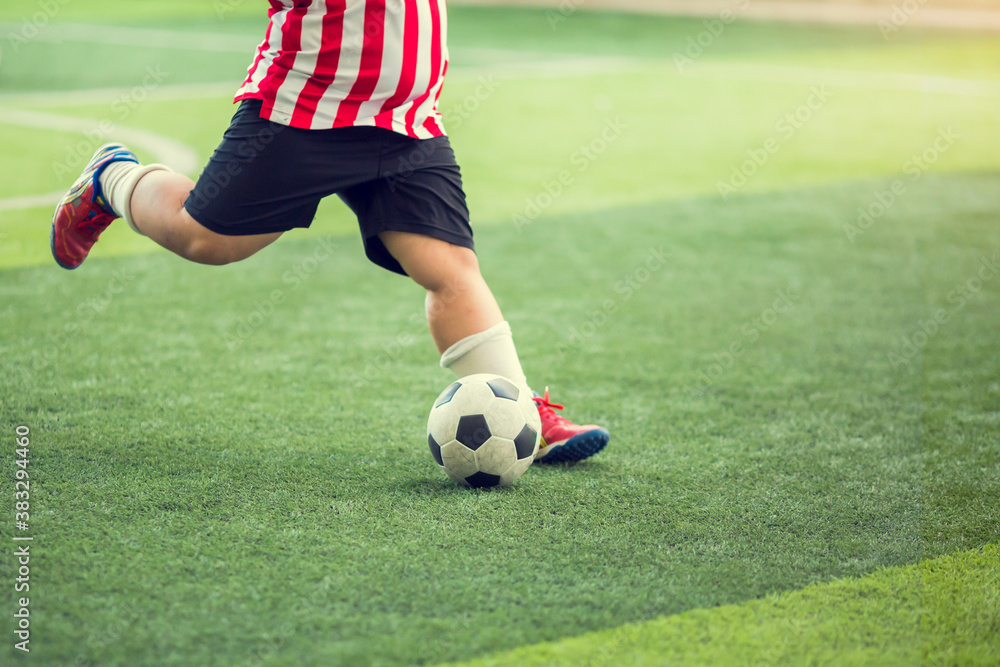 Obraz premium Fat kid soccer player run to shoot ball to goal on artificial turf. Soccer player training for football match.
