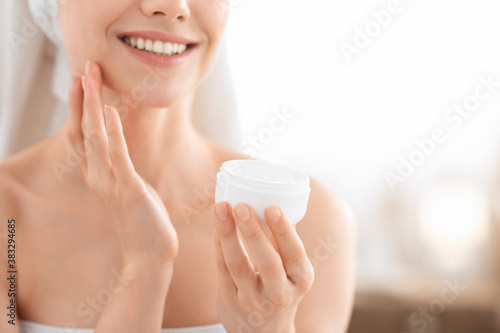 Фотография Unrecognizable smiling woman applying face cream, copy space