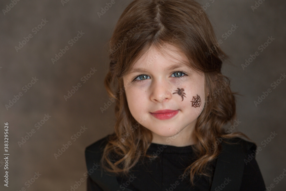 Little girl in halloween costume with web and spyder on her face closeup