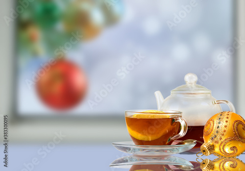 Cup of tea and christmas ball on background of decorated christmas tree