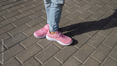 Girl in pink sneakers on cobblestone street. kid's teenagers shoes