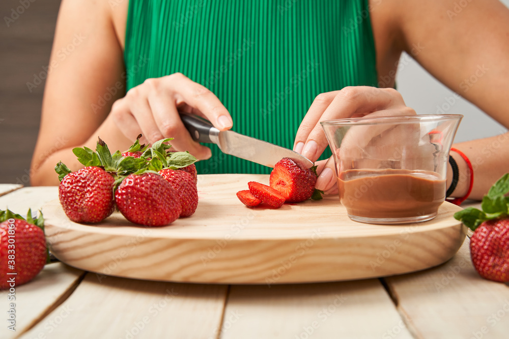 Woman cutting up some strawberries to take them dipped in chocolate.