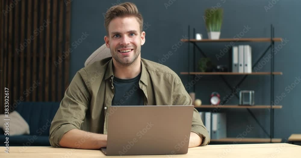 Portrait of young Handsome Freelancer or Student is working studying from Home. Cute Guy is using his Laptop, texting, chatting after looking into the Camera. Online Surfing Lifestyle. Distantly Job. Portrait of young Handsome Freelancer or Student is working studying from Home. Cute Guy is using his Laptop, texting, chatting after looking into the Camera. Online Surfing Lifestyle. Distantly Job.