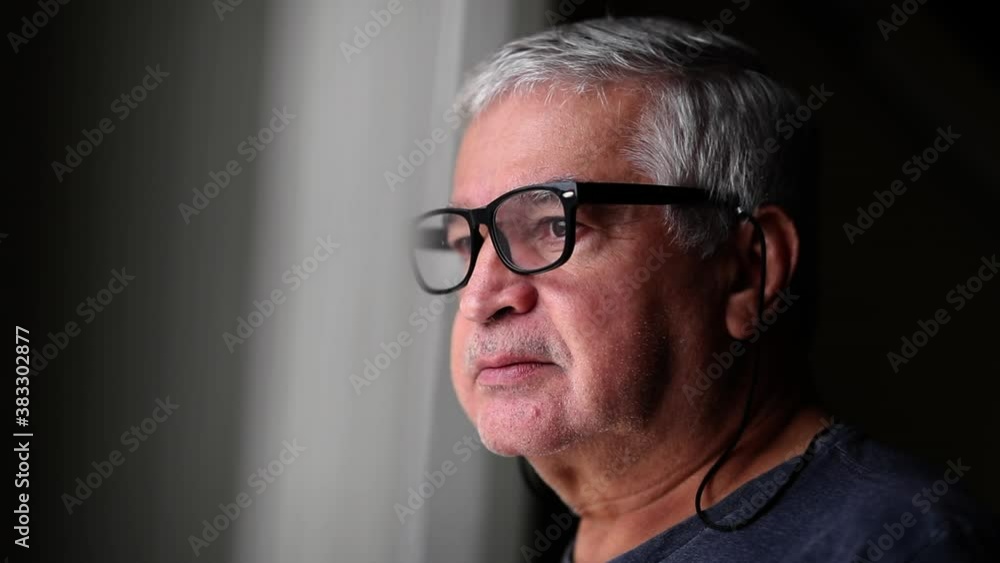 Older man standing by window looking out Older man standing by window looking out