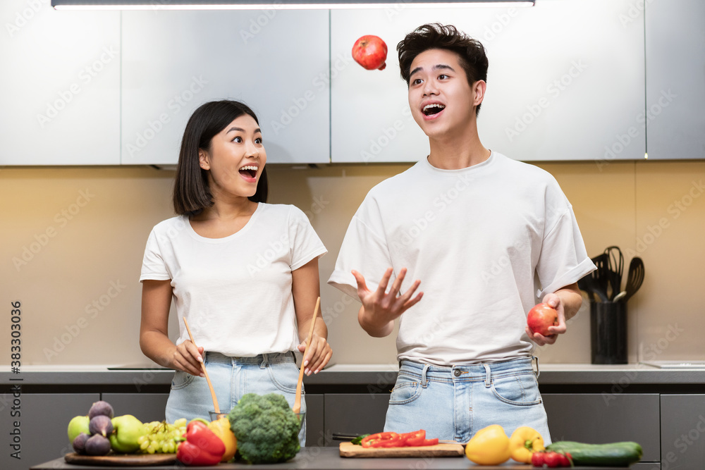 Φωτογραφία Cheerful Japanese Couple Cooking Having Fun Juggling Fruits In Kitchen