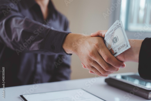 A corporate businessman shakes hands as a man gives and receives dirty cash to bribe a office, the idea of ​​giving and receiving illegal bribes.