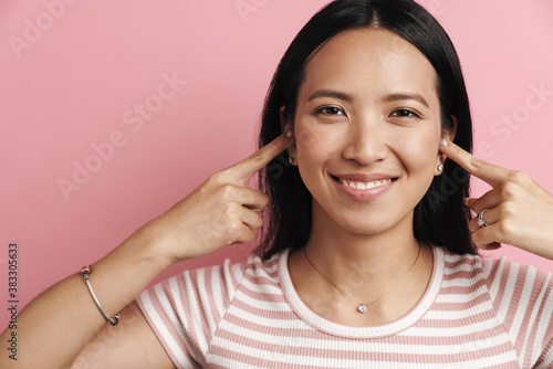 Foto Photo of happy asian woman smiling and plugging her ears