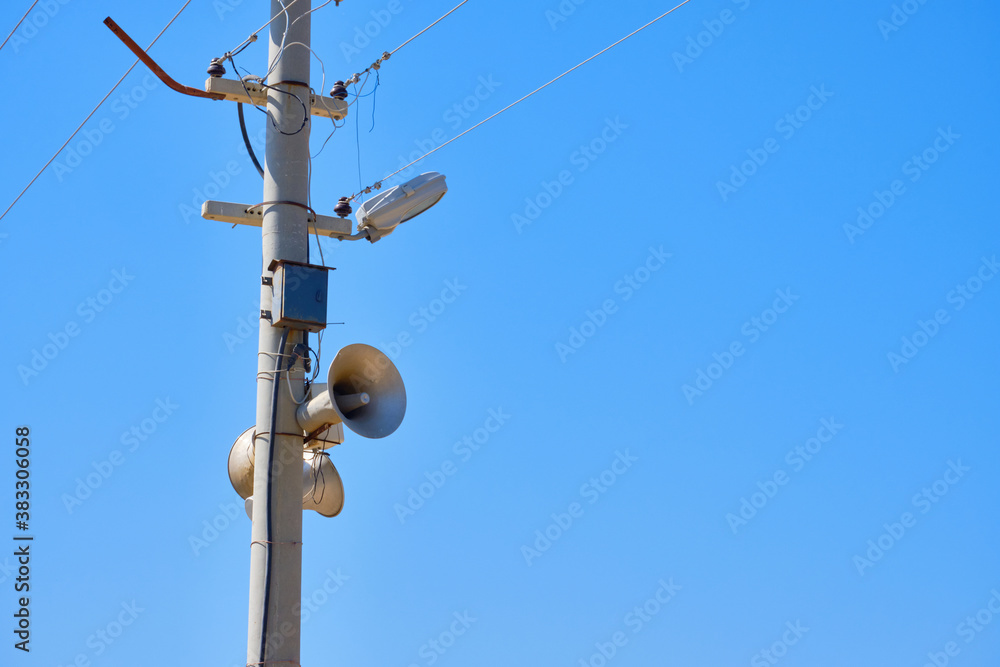 Speaker on the lighting pole. Means of warning in case of emergency. Against blue sky background copy space Speaker on the lighting pole. Means of warning in case of emergency. Against blue sky background copy space