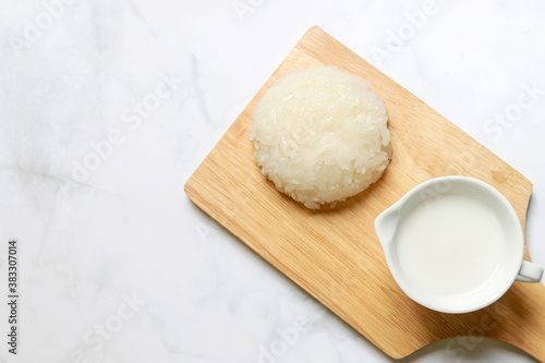 Sticky rice with coconut milk on wooden tray; usually serve with ripe mango or durian. Thai style tropical dessert, glutinous rice eat with tropical fruits.