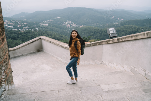 Half length portrait of smiling asian female traveler excited with free time vacation and sightseeing tour, positive woman with backpack enjoying exploring historical place on vacation holiday