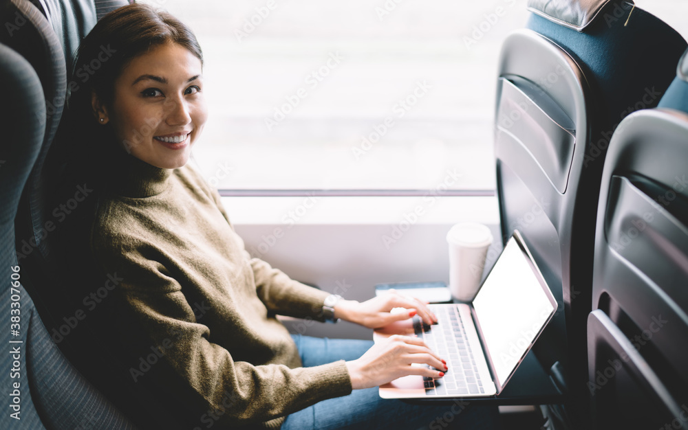 Young female student doing homework with laptop in train