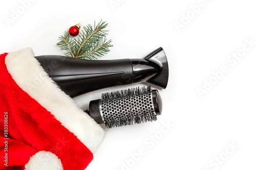 Christmas composition. Hairdressing tools and a spruce branch on a white background, hair dryer, comb. Template for a postcard or information about a hair salon. Flat lay, copy space