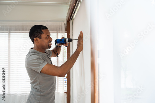 Εκτύπωση καμβά Smiling African American male using electric drill on the wall