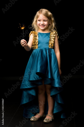 Charming Girl in Nice Dress Looking with Admiration at Fire Sparkler.