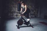 Fit sportswoman training on cycling machine in studio