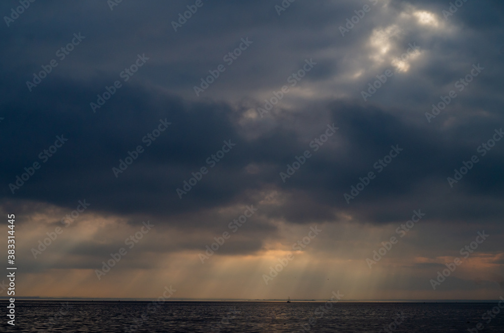 sun rays shine through the clouds at sunrise, sea background.