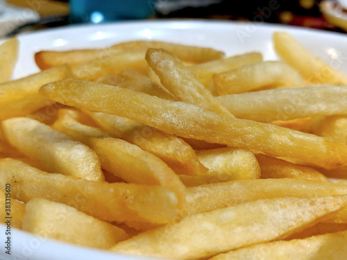 A white plate full of delicious french fries macro isolated snack side view closeup