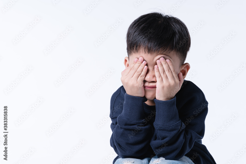 Asian boy touching his head with hurt expression Asian boy touching his head with hurt expression