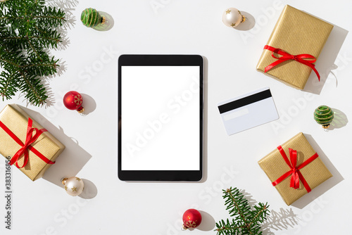Christmas online shopping banner. Tablet with white screen for your design on white background with credit card, gift boxes and Christmas decorations. Winter holidays sales. Top view, copy space © Dina Photo Stories