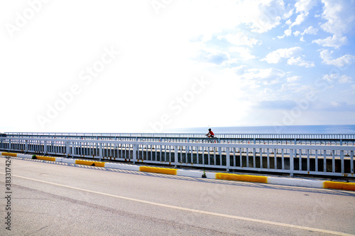 A woman cycling on the road by the sea.