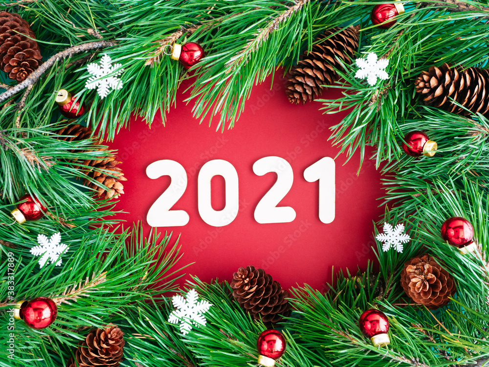 Christmas wreath and numbers 2021. Creative layout of Christmas tree branches, cones and toys on a red background, top view, copy space, flat layout. The concept of the New year and Christmas Christmas wreath and numbers 2021. Creative layout of Christmas tree branches, cones and toys on a red background, top view, copy space, flat layout. The concept of the New year and Christmas