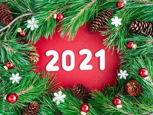 Christmas wreath and numbers 2021. Creative layout of Christmas tree branches  cones and toys on a red background  top view  copy space  flat layout. The concept of the New year and Christmas
