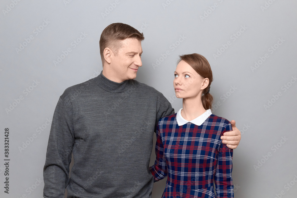 Portrait of serious woman and joyful man hugging and looking at each other Portrait of serious woman and joyful man hugging and looking at each other
