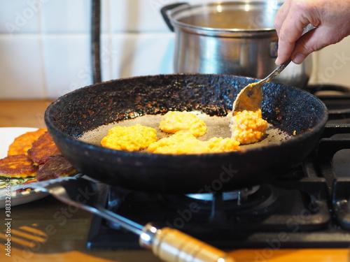 The process of frying natural dietary pumpkin and millet pancakes in a pan on the stove. An elderly woman's homemade food.Country style.