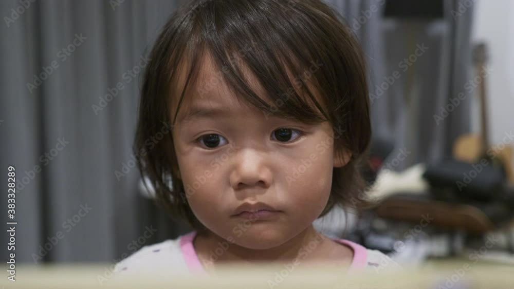 Medium Close of a 2 year old toddler watching a video on an iPad, tablet. Medium Close of a 2 year old toddler watching a video on an iPad, tablet.
