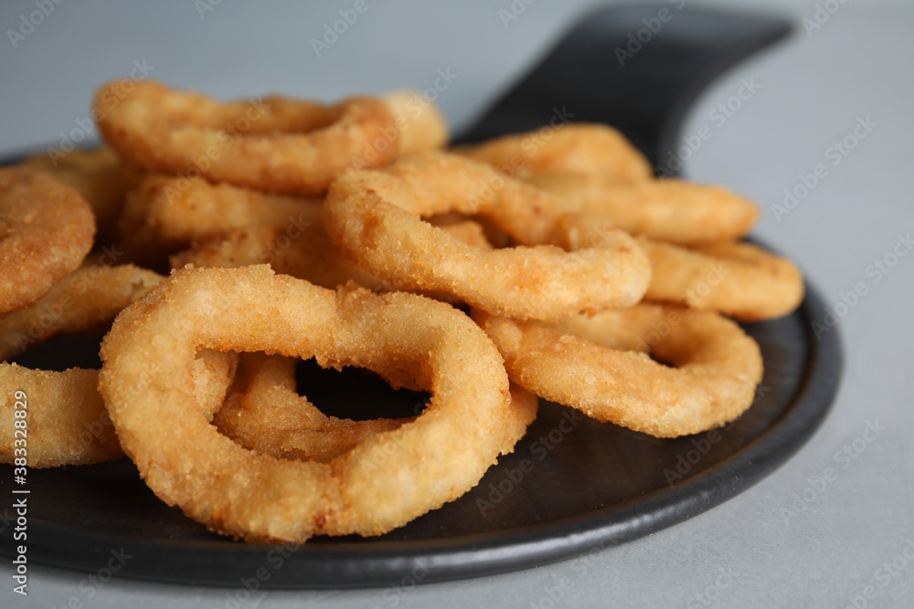 Slate plate with fried onion rings on grey table, closeup Slate plate with fried onion rings on grey table, closeup