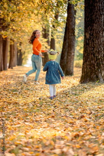 Smiling young family running into leaves on an autumns day. active games