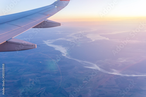 Passenger plane flying above the clouds. View from the wing of the plane. Travel concept