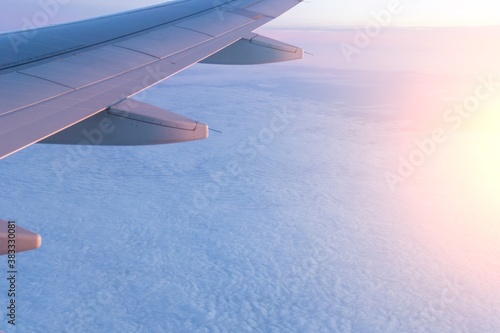 Passenger plane flying above the clouds. View from the wing of the plane. Travel concept photo