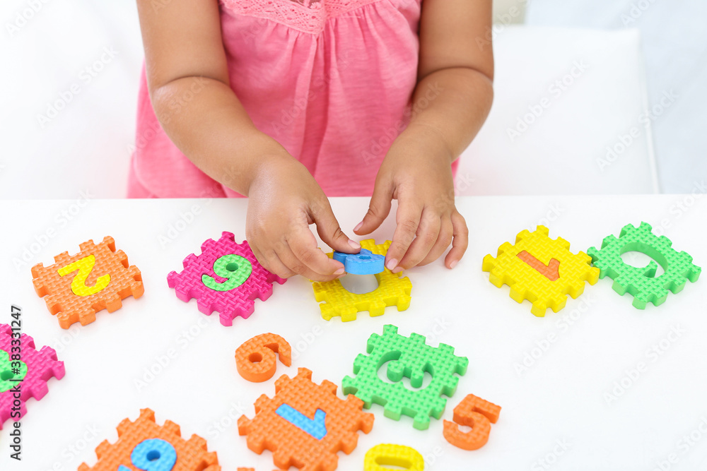 Little girl playing with colorful puzzles at white table, closeup. Educational toy Little girl playing with colorful puzzles at white table, closeup. Educational toy