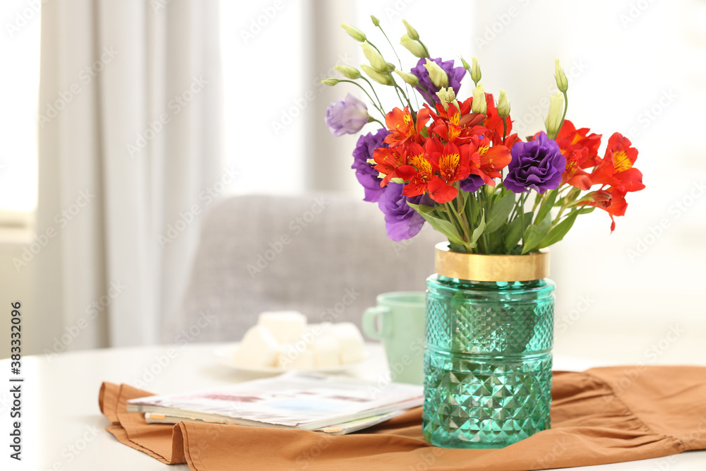 Glass vase with fresh flowers and magazines on table indoors. Space for text Glass vase with fresh flowers and magazines on table indoors. Space for text