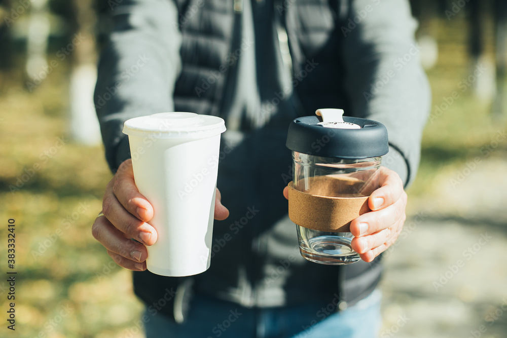 Men holding takeaway coffee cup and disposable paper cup with plastic lid. Conscious choice Men holding takeaway coffee cup and disposable paper cup with plastic lid. Conscious choice