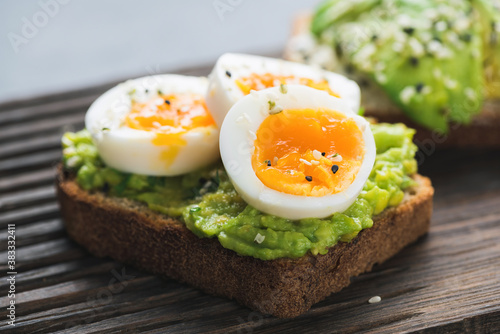 Avocado toast with egg on wooden board, closeup view
