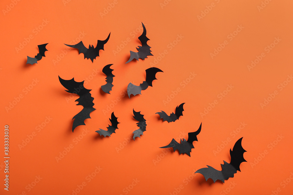 Fototapeta premium Paper bats on orange background, flat lay. Halloween decor