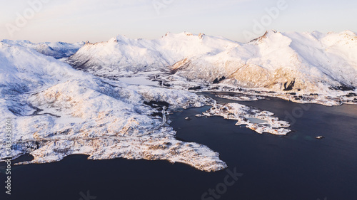 Breathtaking bird s eye view of majestic fjord mountains covered with snow in winter. Aerial view of scenery rock peaks  picturesque beautiful nature landscape. Lofoten Island surrounds by Nordic sea