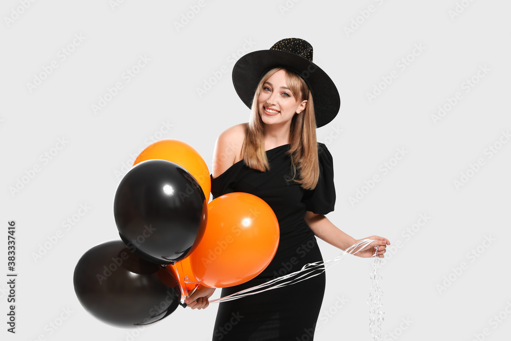 Beautiful woman in witch costume with balloons on white background. Halloween party Beautiful woman in witch costume with balloons on white background. Halloween party