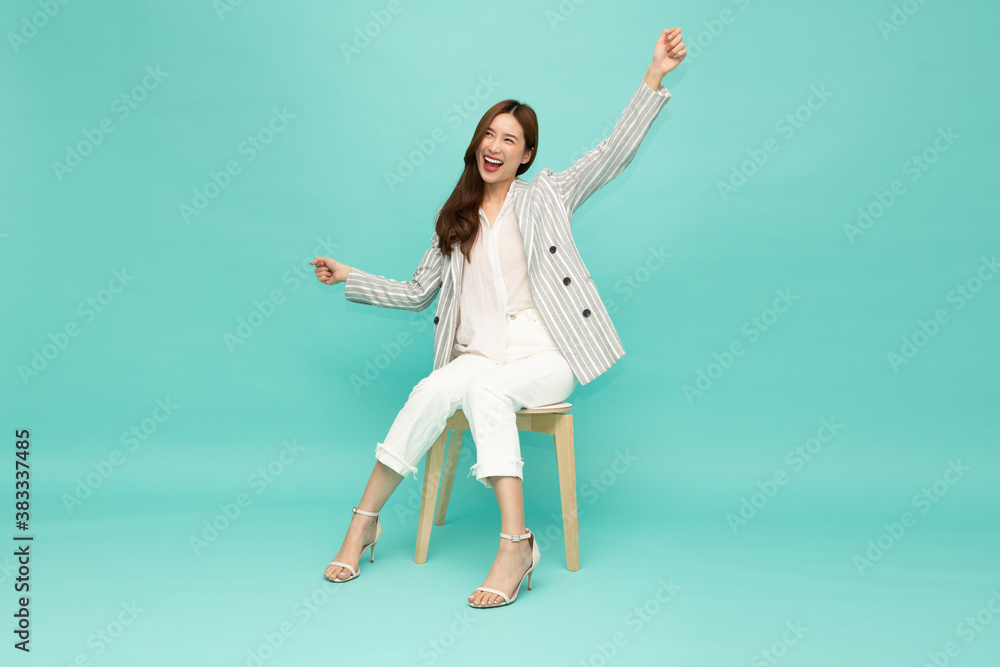 Attractive beautiful Asian woman sitting on white modern chair and hands up raised arms from happiness, Excited businesswoman winner success concept Attractive beautiful Asian woman sitting on white modern chair and hands up raised arms from happiness, Excited businesswoman winner success concept