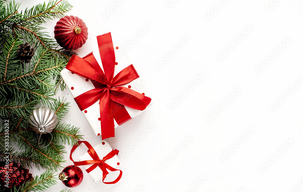 Christmas composition on a white background with white gift boxes, with a red ribbon with fir branches, toys, copy space for your congratulations Christmas composition on a white background with white gift boxes, with a red ribbon with fir branches, toys, copy space for your congratulations