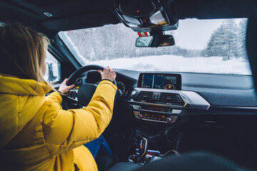 Professional female driver explore destination by car having good winter wheel for safe travel, woman traveler driving automobile on wildwood nature landscape