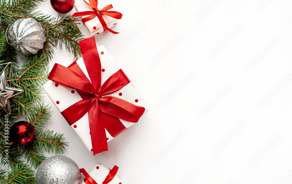 Christmas composition on a white background with white gift boxes, with a red ribbon with fir branches, toys, copy space for your congratulations Christmas composition on a white background with white gift boxes, with a red ribbon with fir branches, toys, copy space for your congratulations
