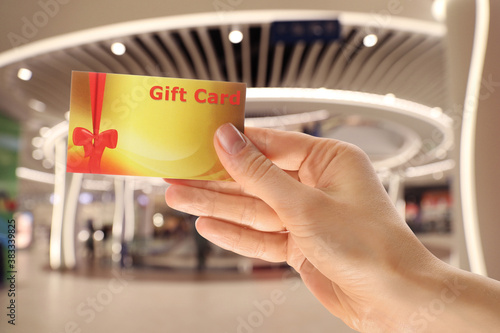 Woman holding gift card in shopping mall, closeup